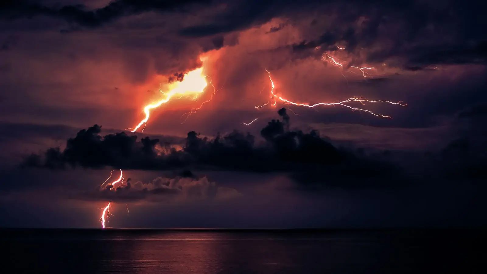 Lightning storm clouds over water at night