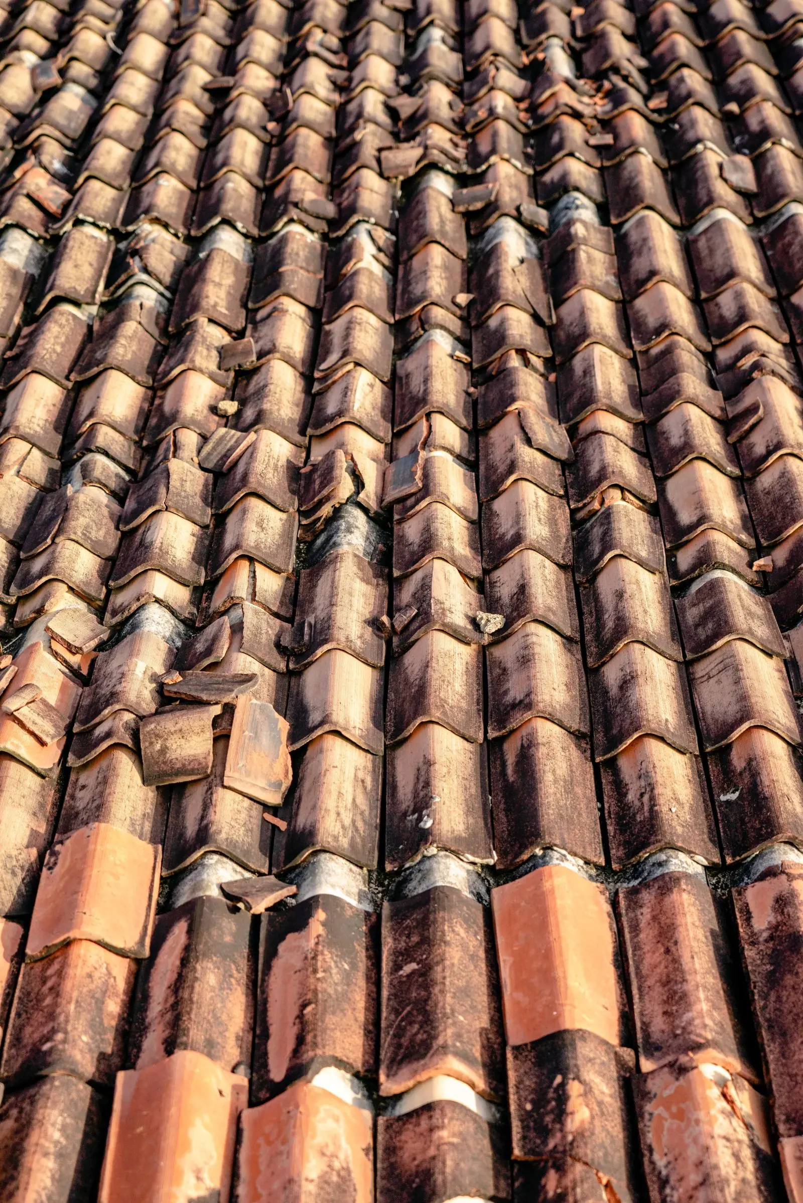 Weathered, damaged clay roof tiles prone to leaking