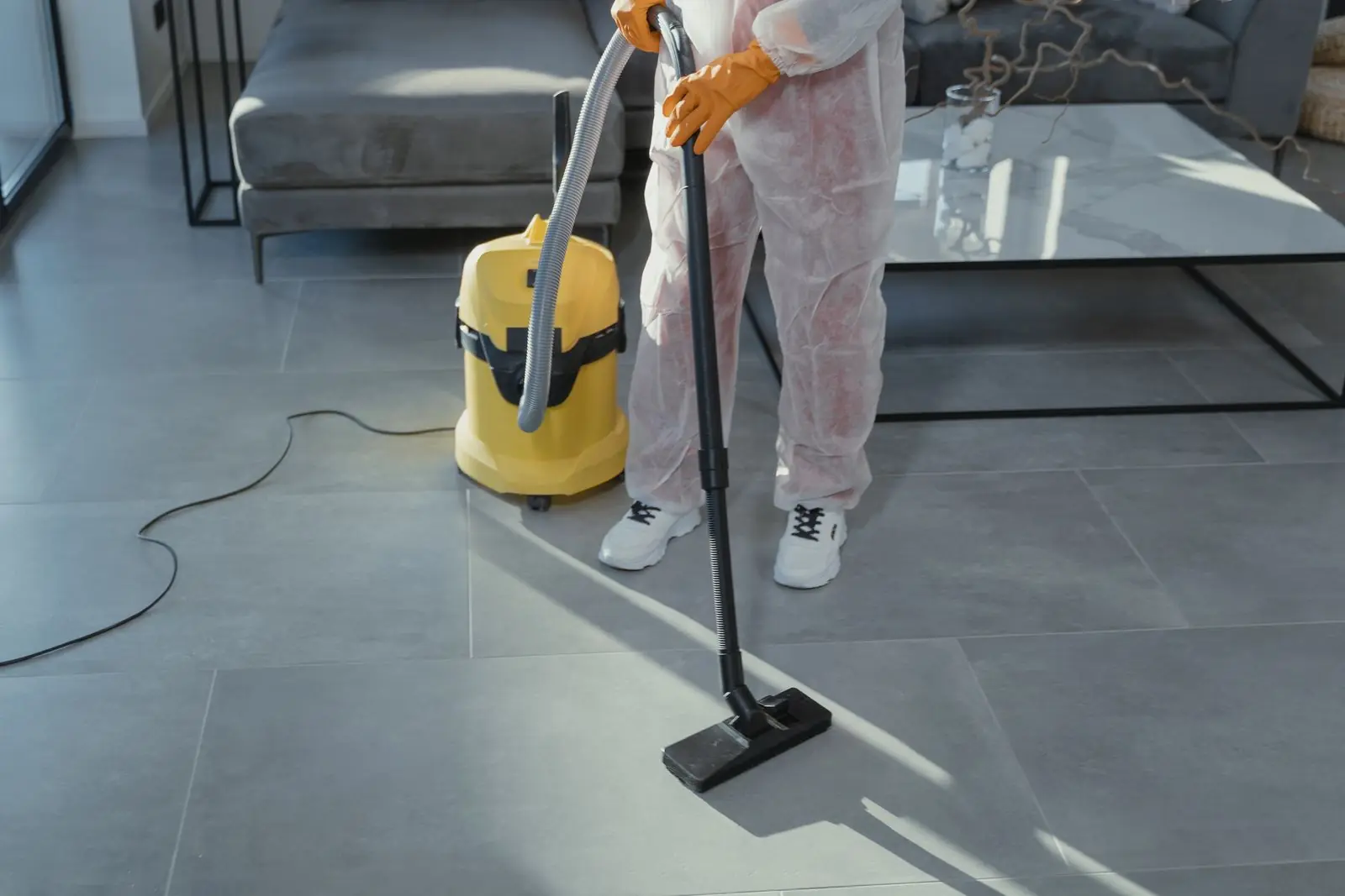Worker in protective coveralls using a wet/dry vacuum for water extraction