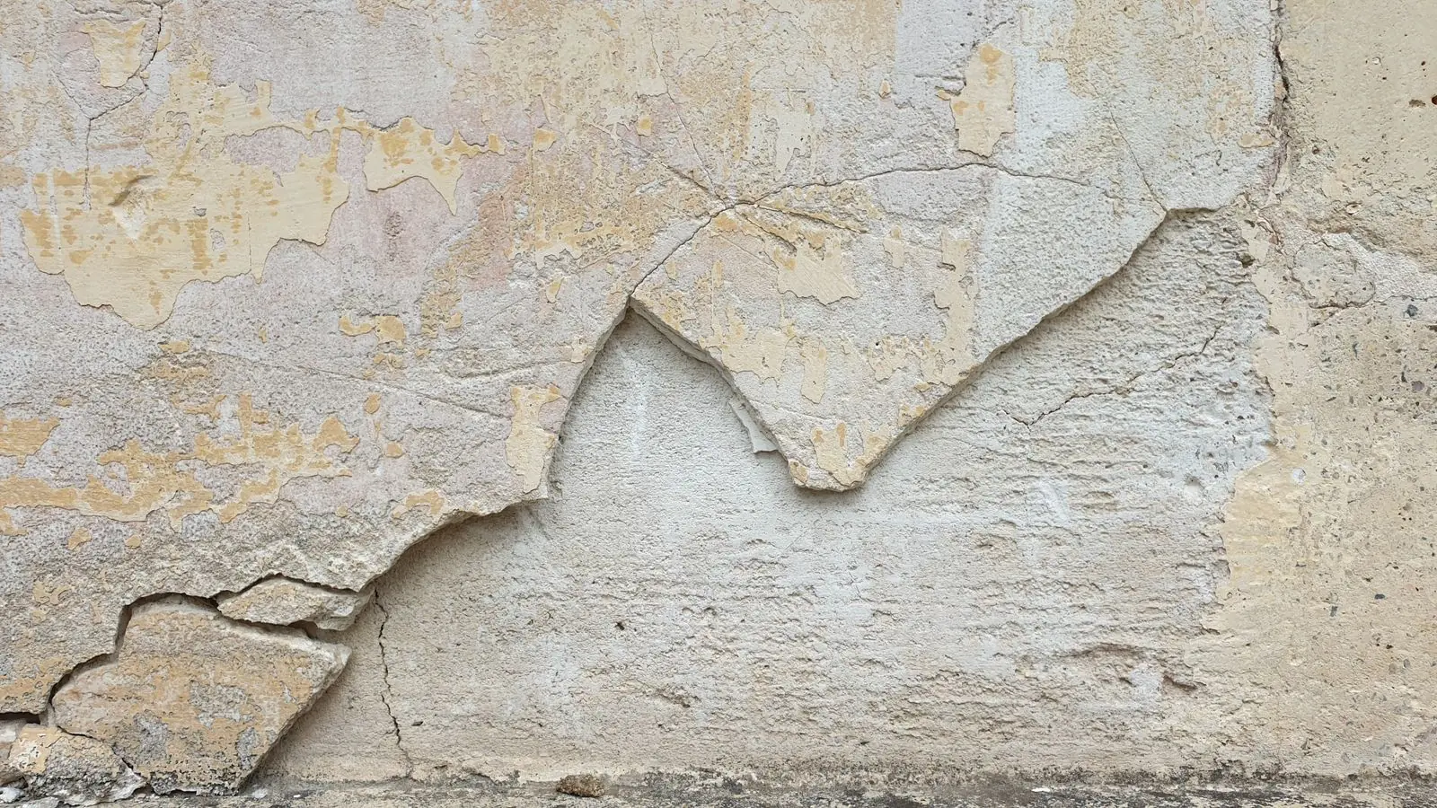 Cracked and peeling plaster showing water-damage staining