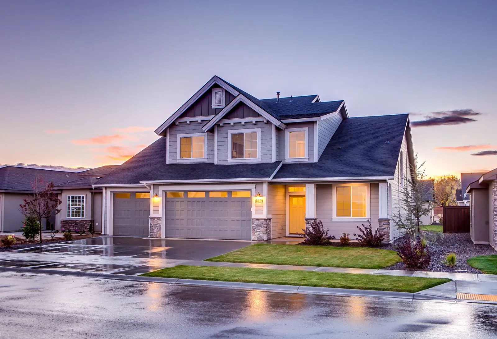 Suburban two-story home with a dark shingle roof at dusk